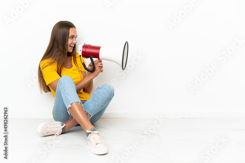Young girl sitting on the floor shouting through a megaphone