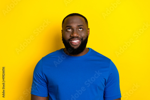 Portrait of attractive cheerful guy looking up copy blank space ad isolated over bright yellow color background