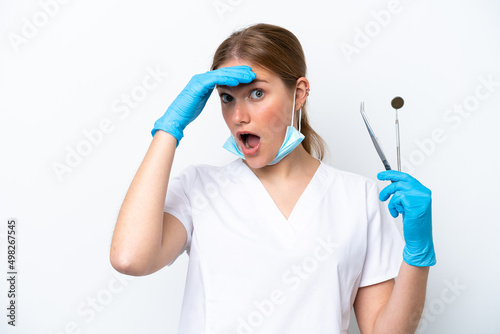 Dentist caucasian woman holding tools isolated on white background doing surprise gesture while looking to the side