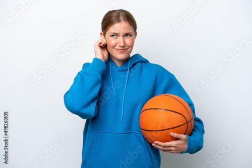 Young caucasian woman playing basketball isolated on white background frustrated and covering ears © luismolinero