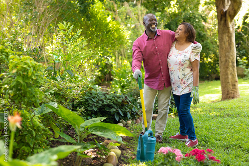 Cheerful african american senior couple gardening together in backyard