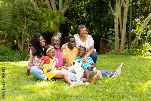 Playful african american multi-generational family with soccer ball sitting in backyard photo