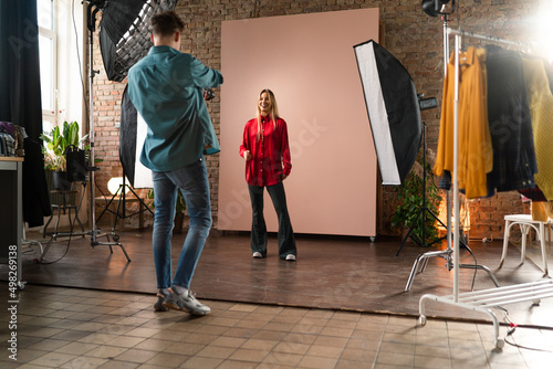 Fotografía Young photographer taking picures of model, backstage of photoshooting in studio