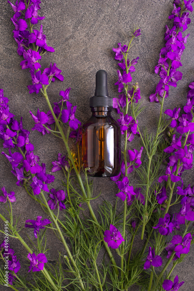 Glass bottle of Lavender essential oil on textural gray background. Natural material. Natural cosmetic skincare bottle container. Modern spring skin care layout. Flat lay, copy space, top view. Perfum Glass bottle of Lavender essential oil on textural gray background. Natural material. Natural cosmetic skincare bottle container. Modern spring skin care layout. Flat lay, copy space, top view. Perfum