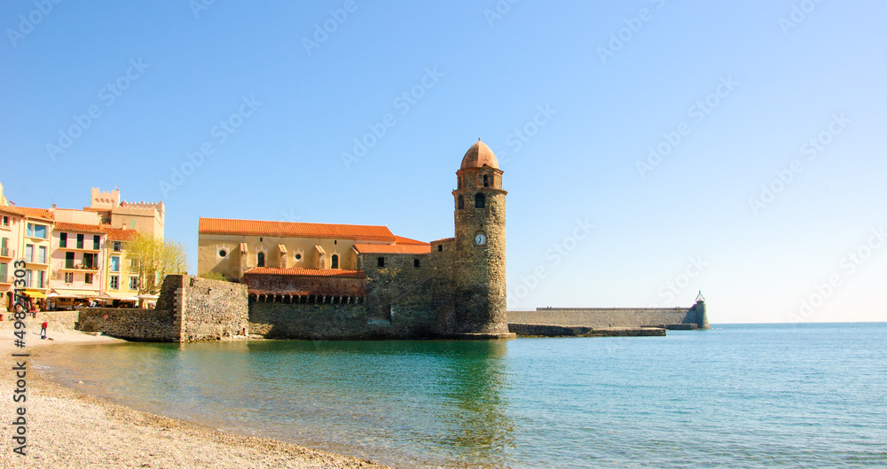 Collioure, France. Beach landscape and Church of Our Lady of Angels in port at background . Picturesque Collioure is popular tourist travel destination.
