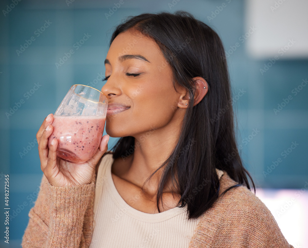 Sipping on a healthy immunity boosting smoothie. Shot of a young woman drinking a healthy smoothie at home. Sipping on a healthy immunity boosting smoothie. Shot of a young woman drinking a healthy smoothie at home.