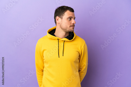 Brazilian man over isolated purple background looking to the side