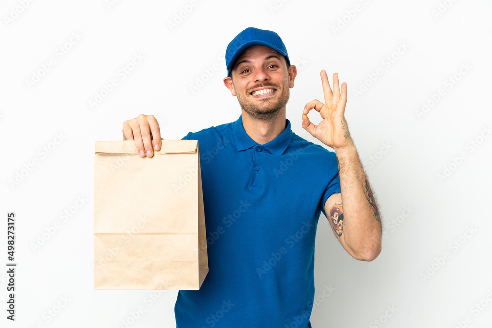 Brazilian taking a bag of takeaway food isolated on white background showing ok sign with fingers Brazilian taking a bag of takeaway food isolated on white background showing ok sign with fingers