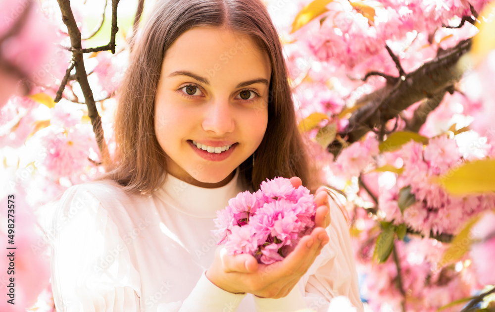Fototapeta premium cheerful teen girl at sakura flower bloom in spring