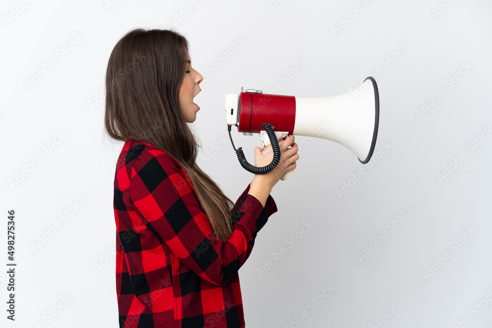 Teenager Brazilian girl isolated on white background shouting through a megaphone to announce something in lateral position Teenager Brazilian girl isolated on white background shouting through a megaphone to announce something in lateral position