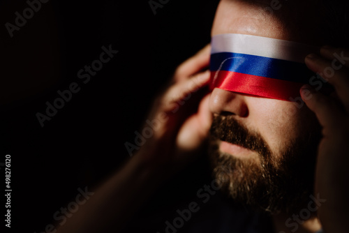 Man with Russian flag blindfold on black background, Russian propaganda closed people's eyes concept.