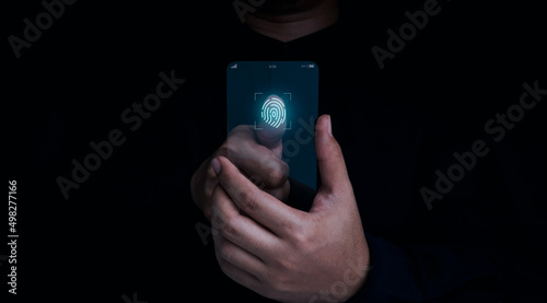 Finger scan icon appeared while man's finger touched on futuristic transparent glass smart mobile phone on dark background. Cyber security, data protection, business privacy technology concept.