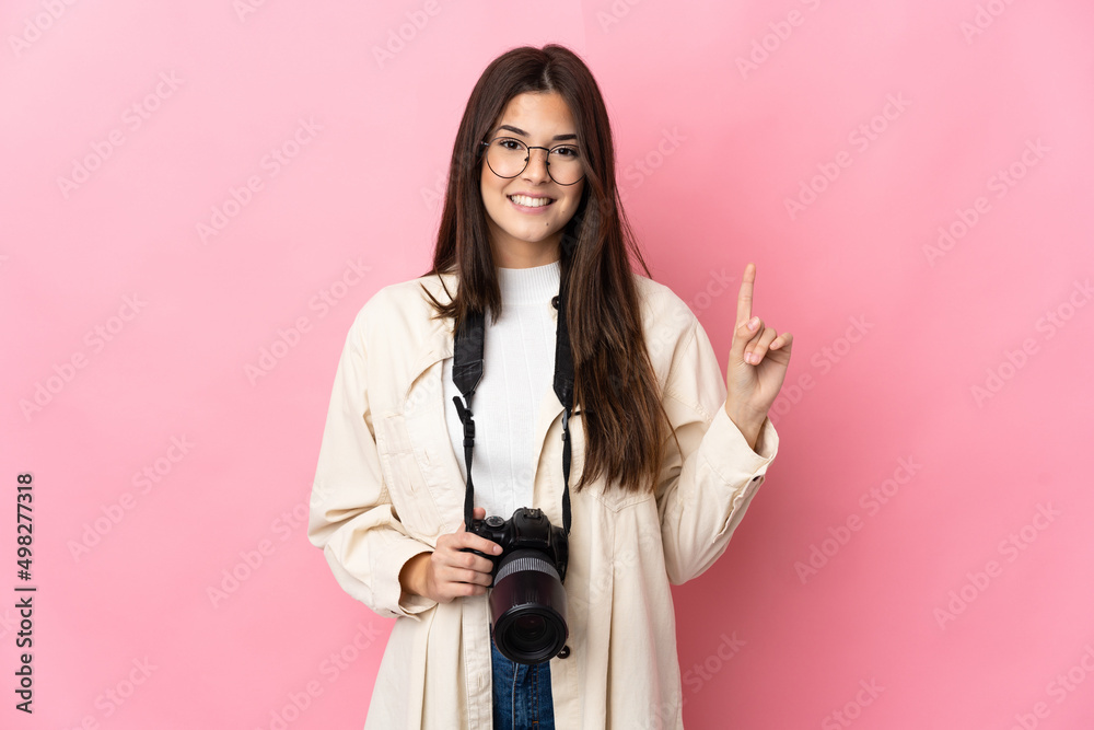 Young photographer Brazilian girl isolated on pink background showing and lifting a finger in sign of the best Young photographer Brazilian girl isolated on pink background showing and lifting a finger in sign of the best
