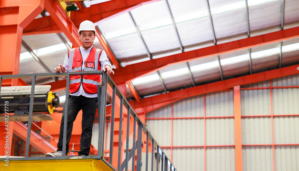 Factory engineer worker operating metal sheet roof machine at Heavy Industry Manufacturing Factory. worker in safety hardhat at factory industrial facilities Factory engineer worker operating metal sheet roof machine at Heavy Industry Manufacturing Factory. worker in safety hardhat at factory industrial facilities