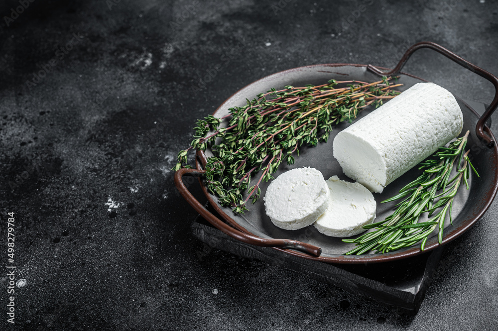 Chevre goat soft cheese with herbs on a tray. Black background. Top