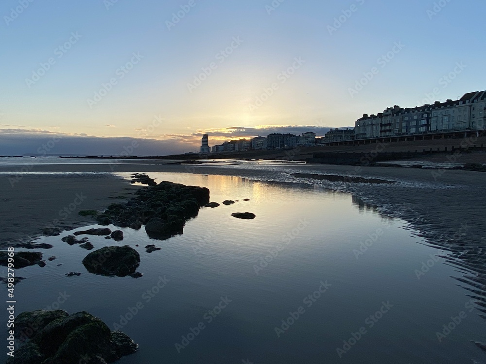 Hastings beach at low tide sea gone out, sunset reflecting on wet sand, Hastings, East Sussex, UK