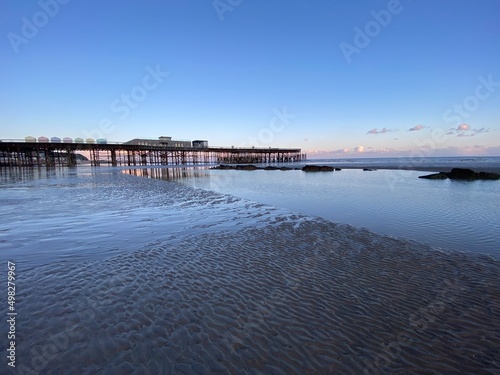 Hastings  East Sussex  UK - Hastings pier with beach huts at low tide reflections on the sand 