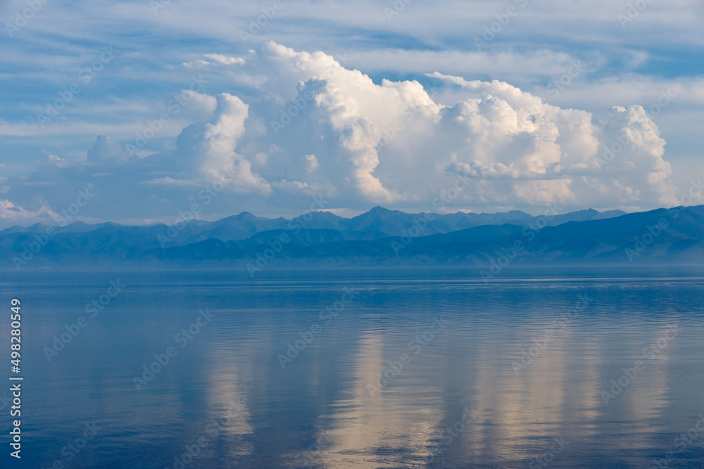 White clouds on Lake Baikal. The clouds are reflected in the water. Evening landscape