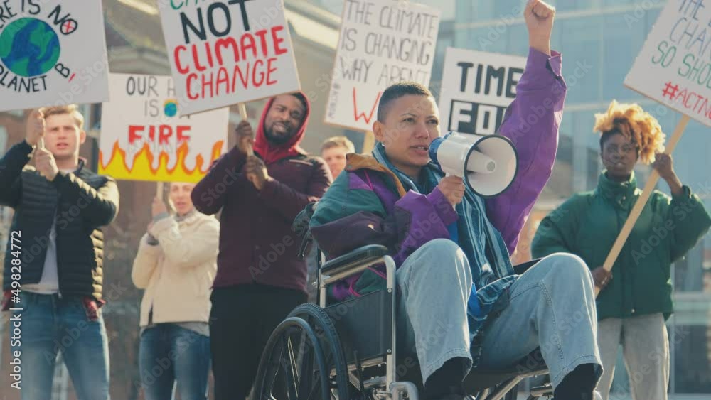 Female protestor in wheelchair using megaphone holding placards and chanting slogans on demonstration march to promote awareness of climate change - shot in slow motion Female protestor in wheelchair using megaphone holding placards and chanting slogans on demonstration march to promote awareness of climate change - shot in slow motion