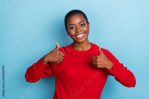 Photo of optimistic millennial braids hairdo lady thumb up wear red pullover isolated on blue color background photo