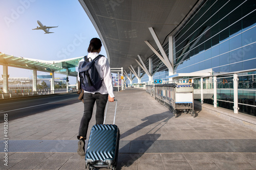 Back view of woman walking with luggage at the airport photo