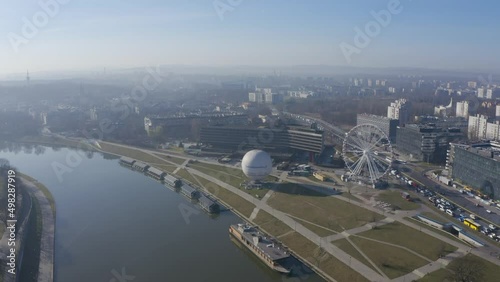 Krakow Poland. River Visla (Vistula), ballon and Ferris wheel. camera moves away from tourist attractions crosse Visla river. Panorama in the morning mist. active traffic on road  photo