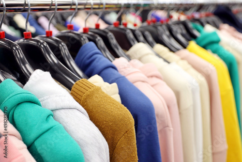 Sweaters, hoodies and blouses in clothing store. Different clothes for women on a rack