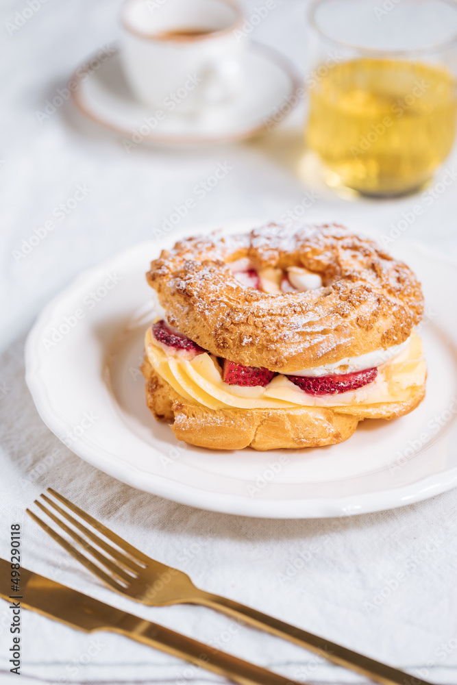 Traditional French Dessert called Paris Brest on a light grey background with powder sugar and strawberries Traditional French Dessert called Paris Brest on a light grey background with powder sugar and strawberries