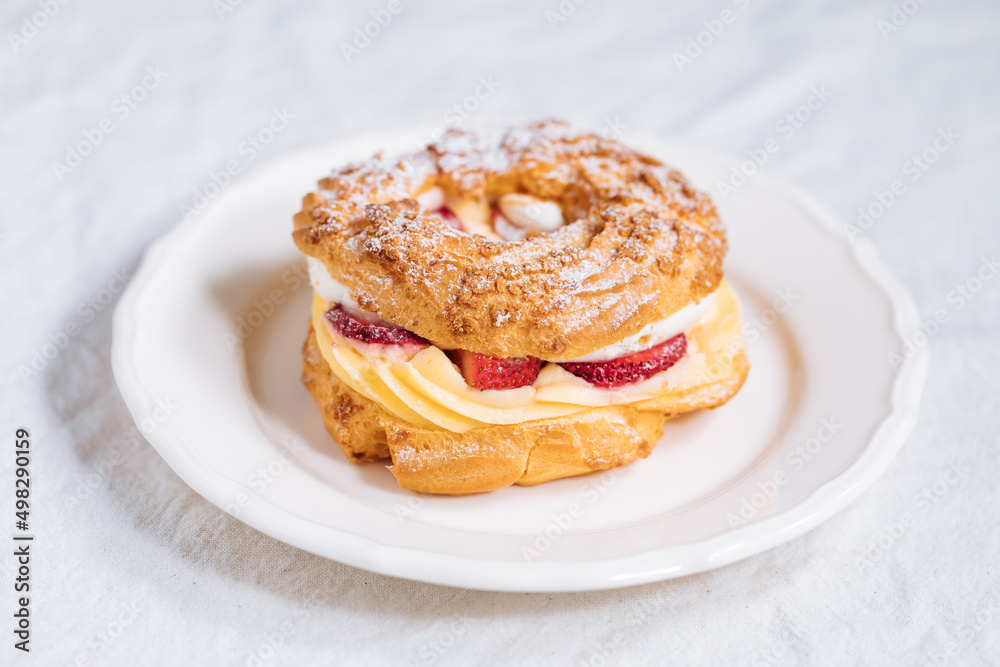 Traditional French Dessert called Paris Brest on a light grey background with powder sugar and strawberries Traditional French Dessert called Paris Brest on a light grey background with powder sugar and strawberries