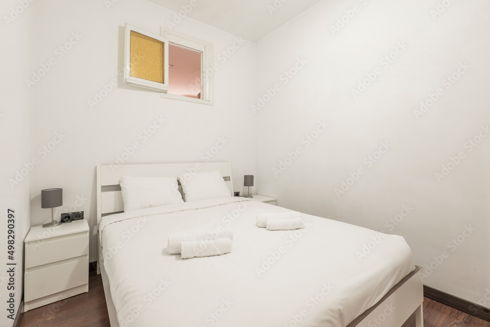 Bedroom with king size bed with white wooden headboard with matching side tables and rolled up white towels Bedroom with king size bed with white wooden headboard with matching side tables and rolled up white towels