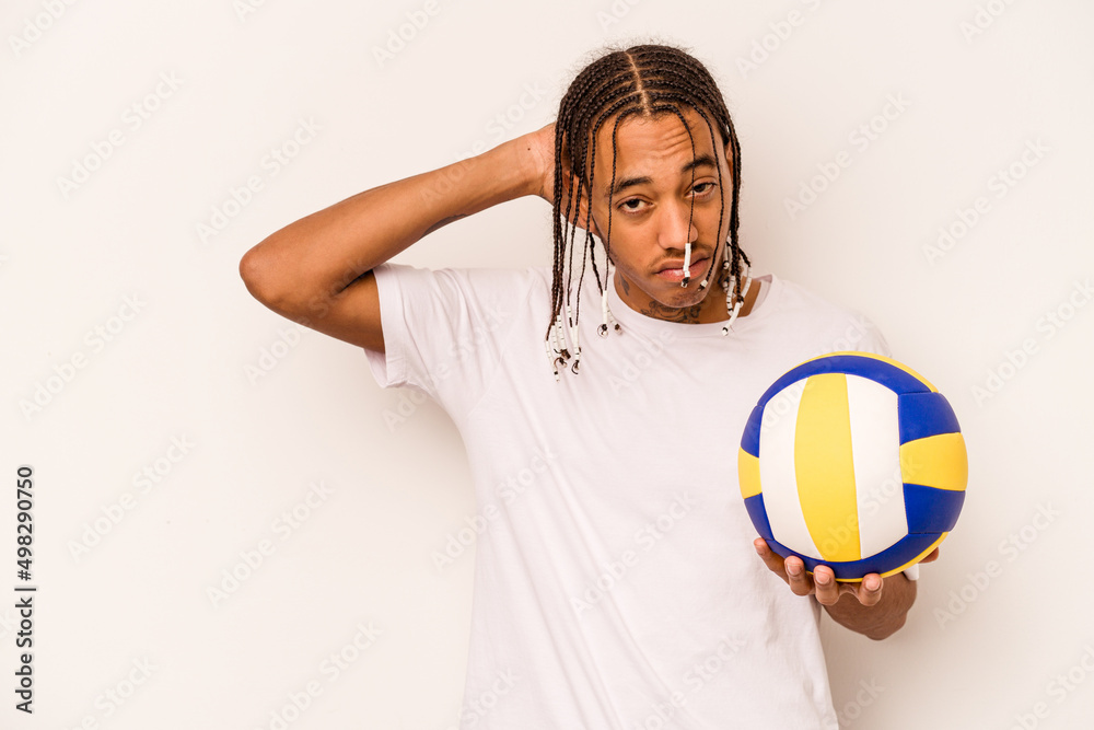 Young African American man playing volleyball isolated on white background touching back of head, thinking and making a choice.