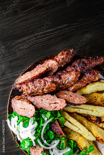 cut Lulia kebab with potato in plate on wooden table background