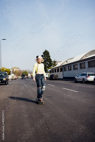 Young nonconformist real beauty queer woman skating outdoors riding skateboard