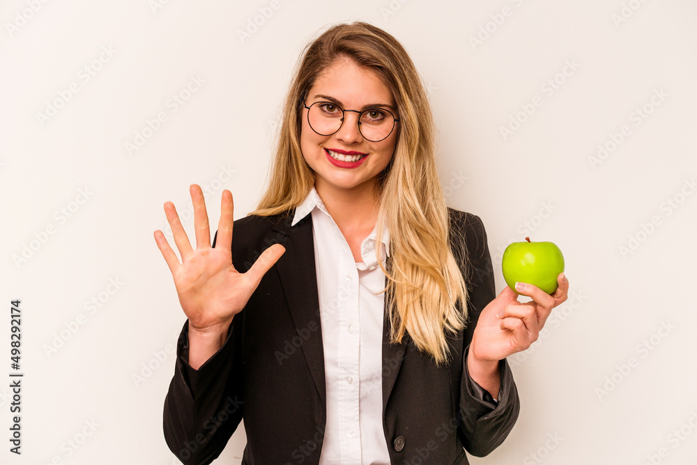 Young business caucasian woman holding an apple isolated on white background smiling cheerful showing number five with fingers. Young business caucasian woman holding an apple isolated on white background smiling cheerful showing number five with fingers.