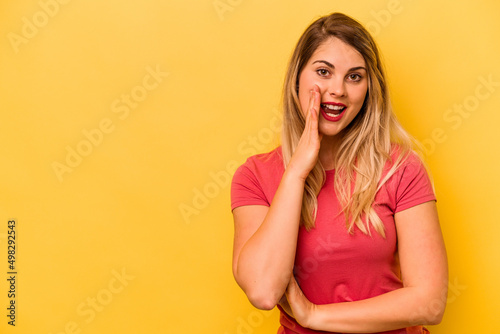 Young caucasian woman isolated on yellow background shouts loud, keeps eyes opened and hands tense.