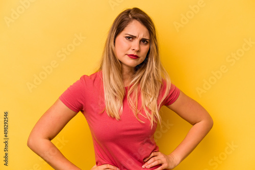 Young caucasian woman isolated on yellow background frowning face in displeasure, keeps arms folded.