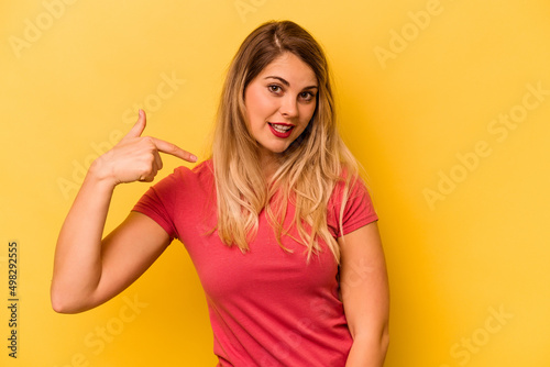Young caucasian woman isolated on yellow background person pointing by hand to a shirt copy space, proud and confident
