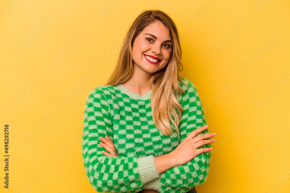 Young caucasian woman isolated on yellow background who feels confident, crossing arms with determination. Young caucasian woman isolated on yellow background who feels confident, crossing arms with determination.