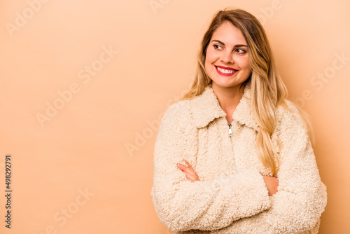 Young caucasian woman isolated on beige background smiling confident with crossed arms.