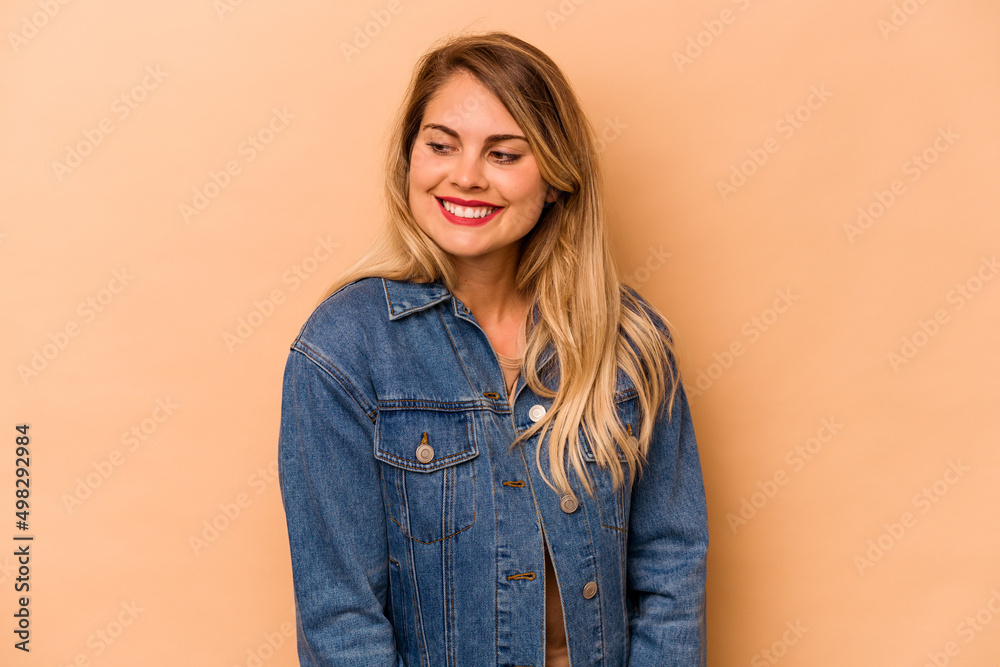 Young caucasian woman isolated on beige background laughs and closes eyes, feels relaxed and happy. Young caucasian woman isolated on beige background laughs and closes eyes, feels relaxed and happy.