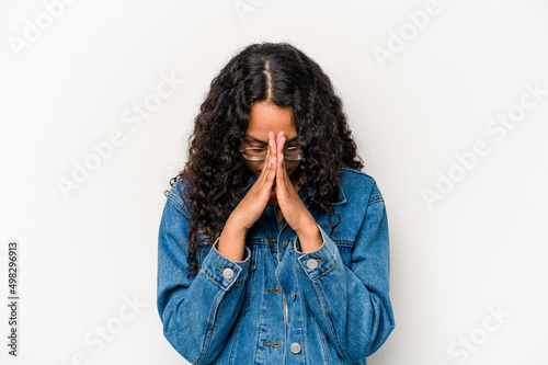 Fototapeta Young hispanic woman isolated on white background praying, showing devotion, religious person looking for divine inspiration