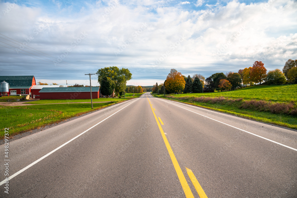 Empty straight stretch of a country road in sunset light in autumn