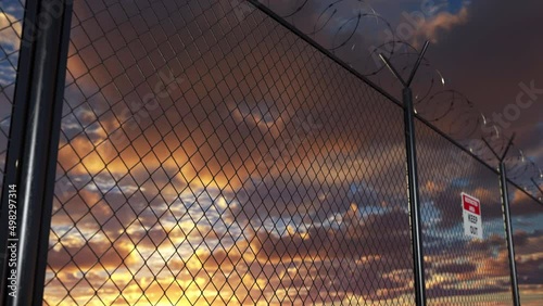 Moving along iron barbed wire fence on the frontier border of the european country. Illegal migration crisis and military conflict justifies installation of the chain link barrier in restricted area.