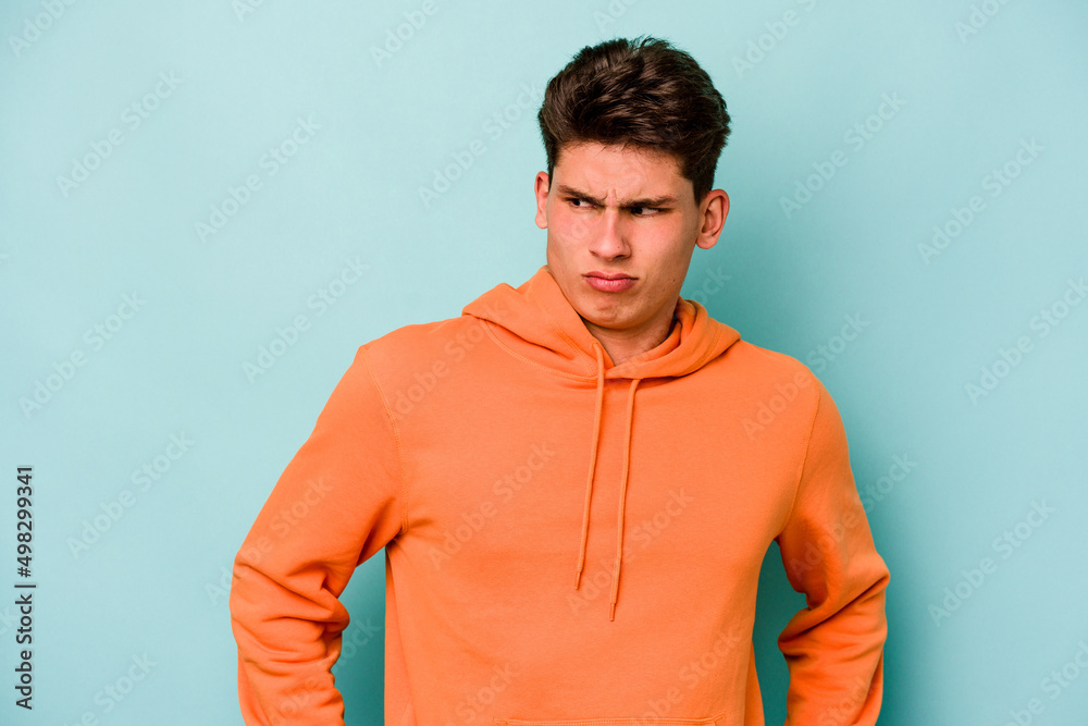 Young caucasian man isolated on blue background confused, feels doubtful and unsure. Young caucasian man isolated on blue background confused, feels doubtful and unsure.