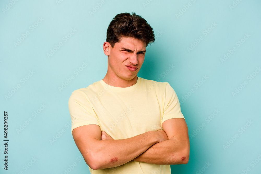 Young caucasian man isolated on blue background suspicious, uncertain, examining you. Young caucasian man isolated on blue background suspicious, uncertain, examining you.