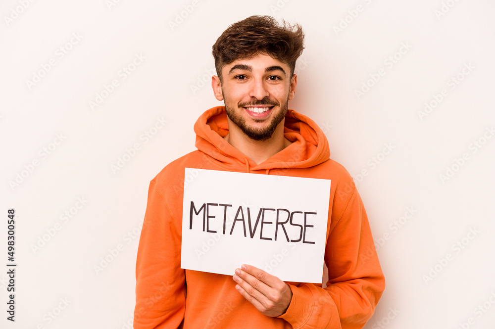 Young hispanic man holding a metaverse placard isolated on white background happy, smiling and cheerful. Young hispanic man holding a metaverse placard isolated on white background happy, smiling and cheerful.