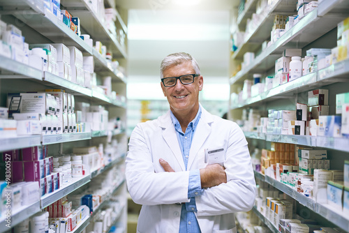 Im confident that youll get better with me to help you. Portrait of a cheerful mature male pharmacist standing with his arms folded while looking at the camera in a pharmacy.