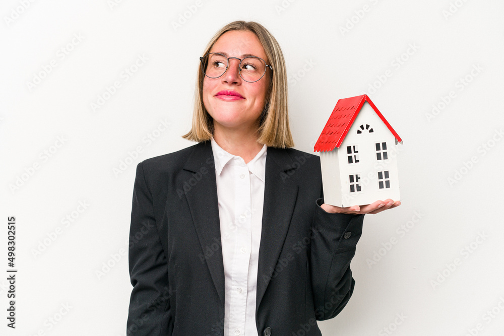 Young business caucasian woman holding a toy house isolated on white background dreaming of achieving goals and purposes Young business caucasian woman holding a toy house isolated on white background dreaming of achieving goals and purposes