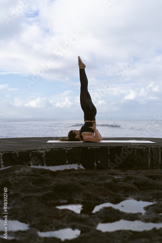 Young woman practice yoga on a beautiful beach at sunrise. Blue sky, ocean, waves, proximity to nature, unity with nature.