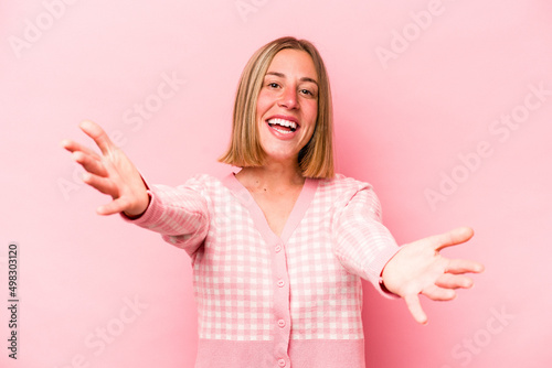 Young caucasian woman isolated on pink background feels confident giving a hug to the camera.